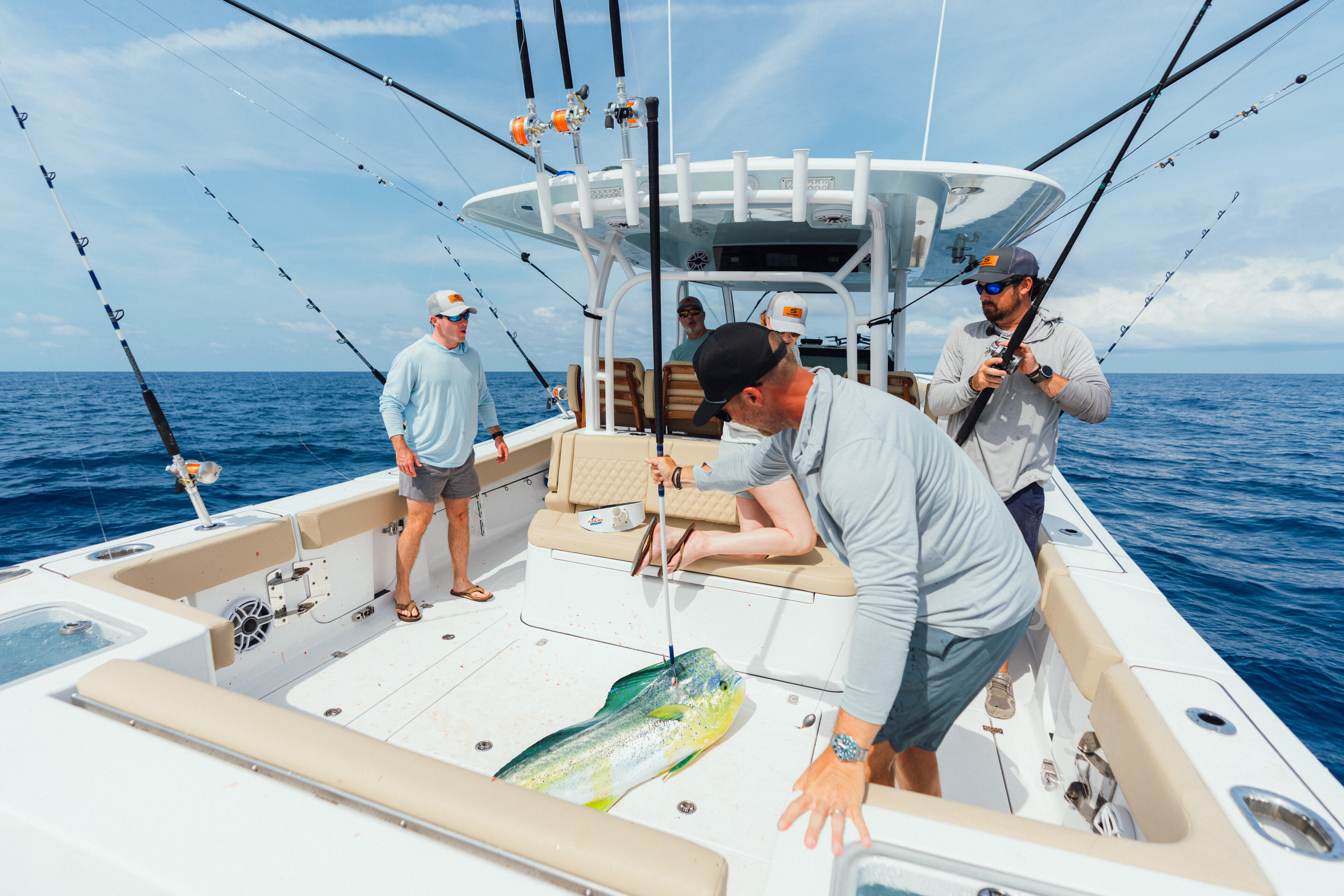 Anglers celebrate a fresh mahi-mahi catch on an offshore fishing boat equipped with multiple rod holders and rigging
