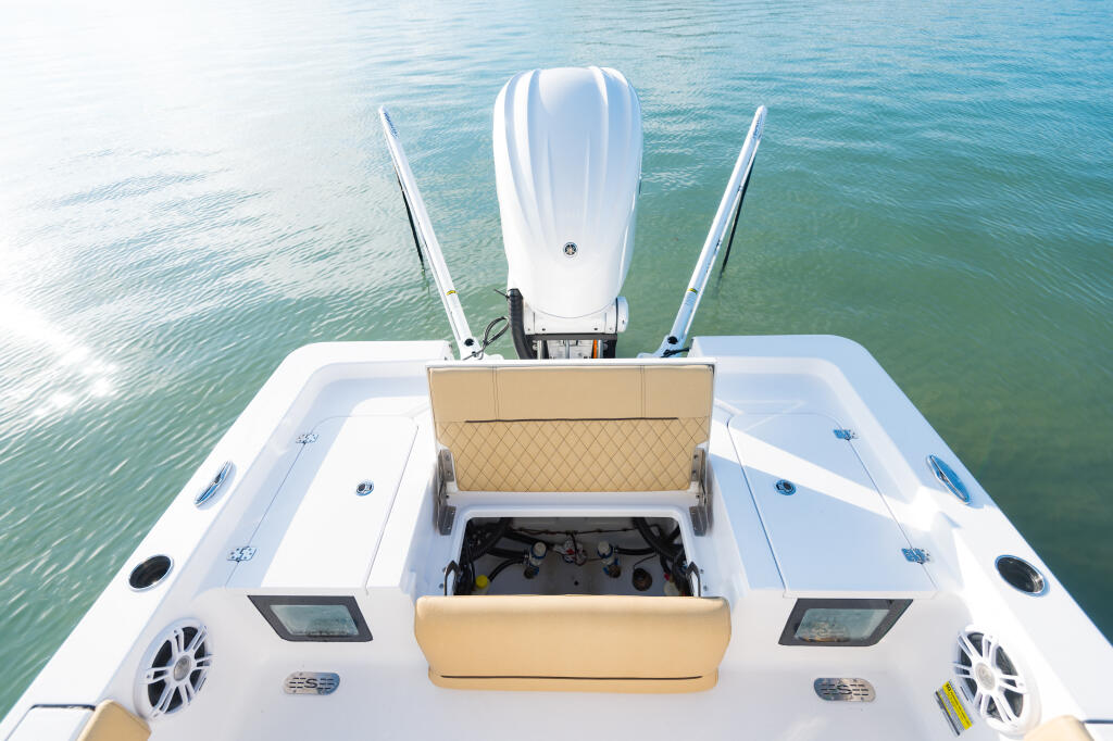 Overhead view of boat's open engine hatch with dual outboard engines and tan seat backs visible from above water