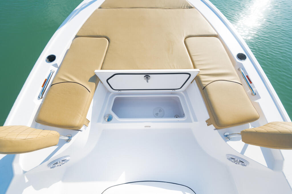 Center console cabin with tan cushioned seating, storage box, and windshield viewed from above on calm turquoise water