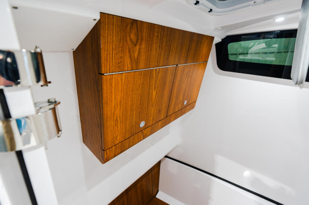 Cabin interior with rich wood cabinetry, white walls, window with green shade, and overhead lighting