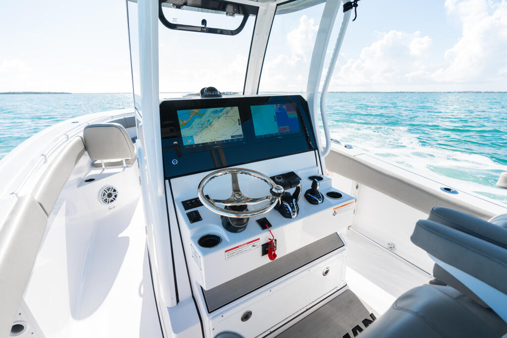 Helm station with dual Garmin chartplotters, steering wheel, and controls overlooking open ocean waters