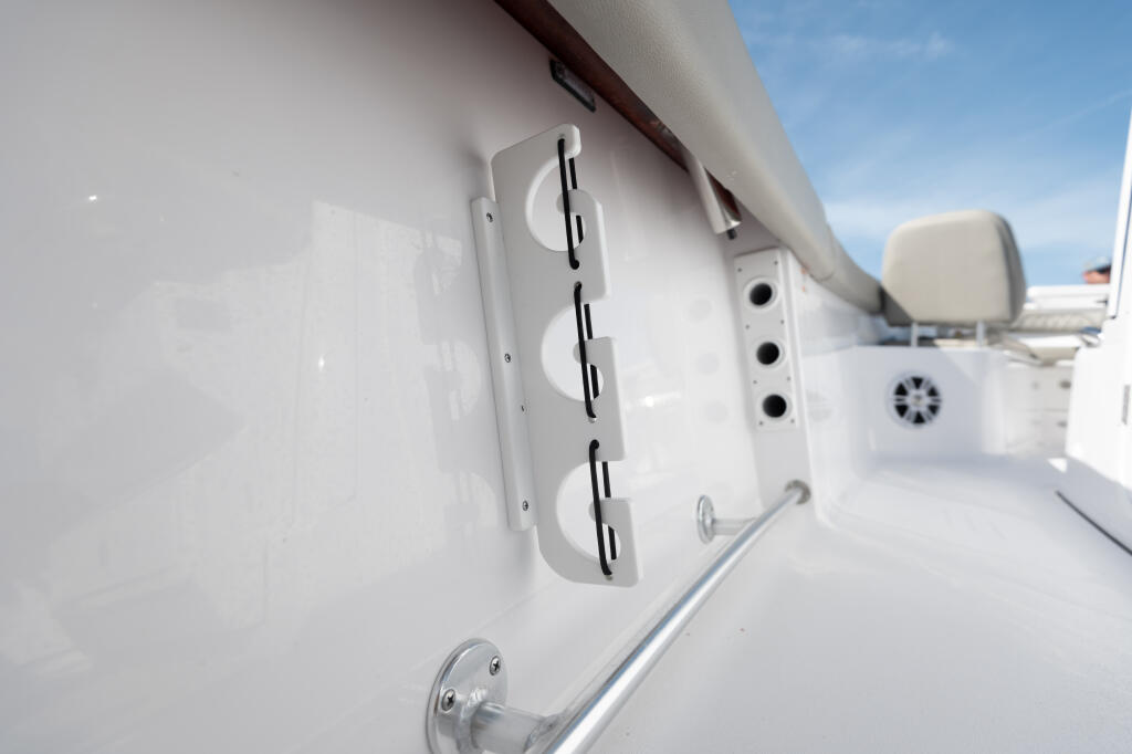 White gunwale-mounted rod racks with black slots on a center console boat's exterior