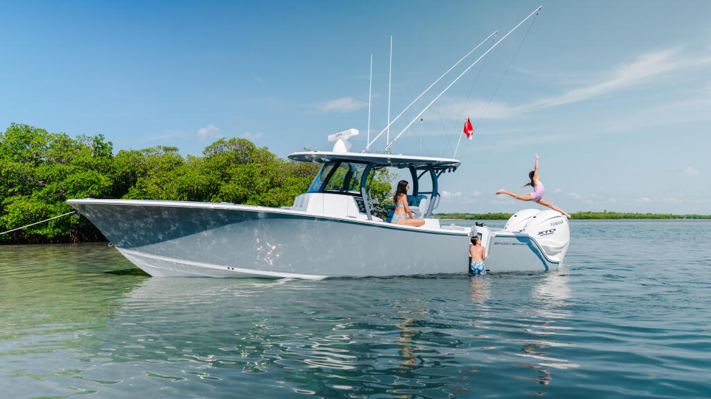 Family enjoying shallow sandbar waters with center console boat, one person diving off swim platform