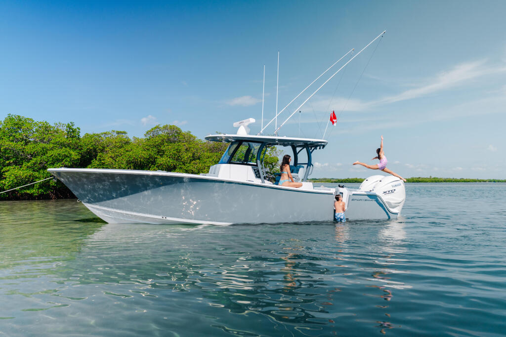 Family enjoying shallow sandbar waters with center console boat, one person diving off swim platform