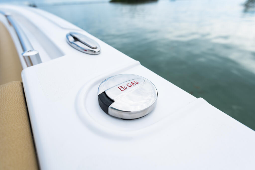 Close-up of dual fuel fill cap on white boat gunwale with calm water in background