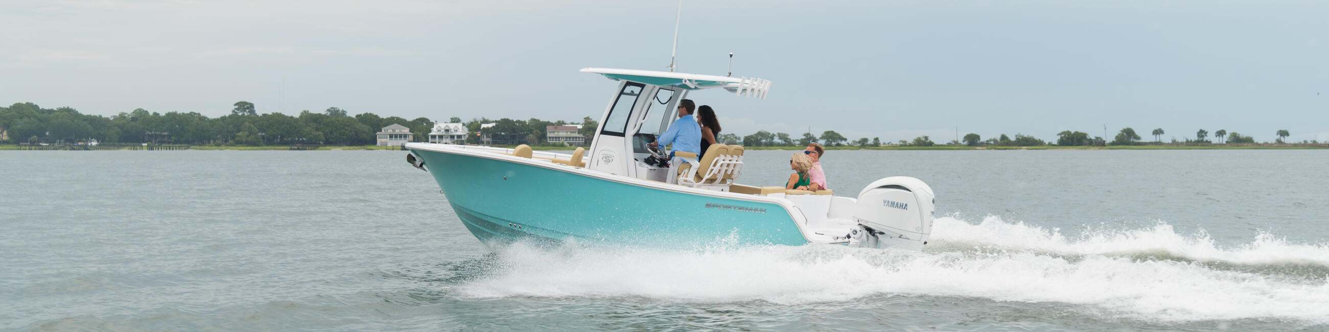 Turquoise center console boat running through shallow coastal waters with passengers aboard