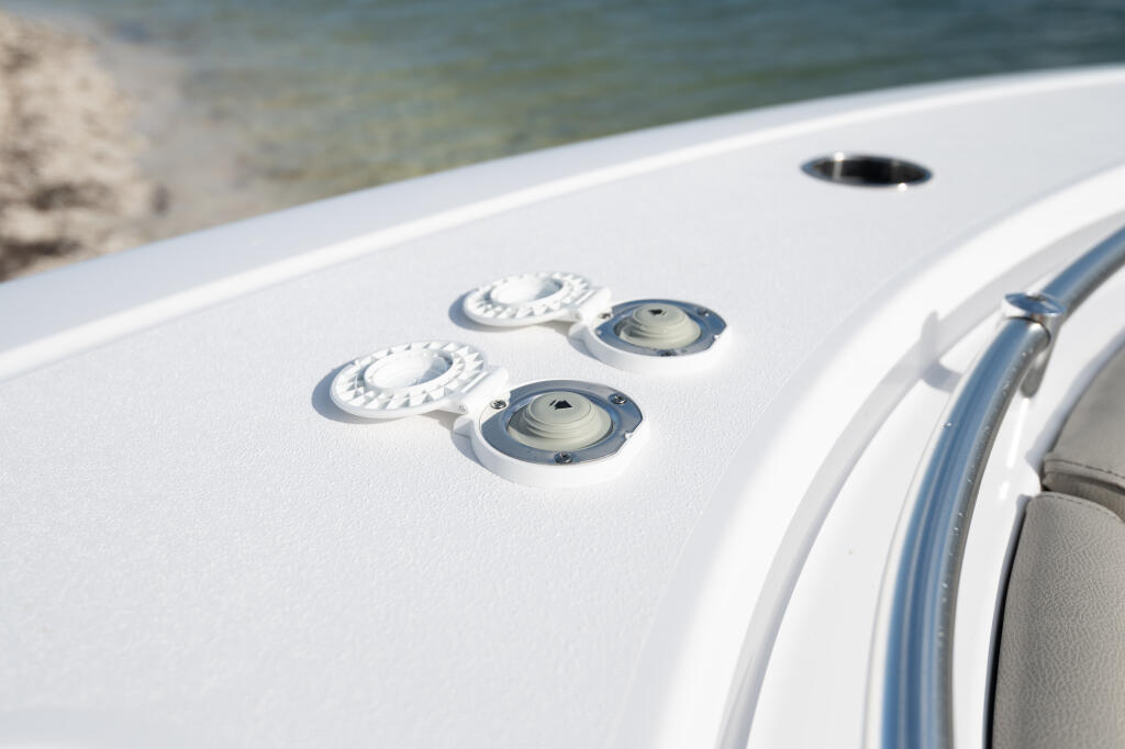 White boat gunwale with anchor control dials and cleats near the water