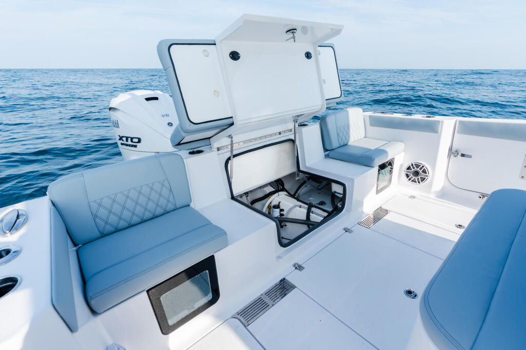 Helm and seating area of a white center console boat with blue cushioned seats and hardtop canopy