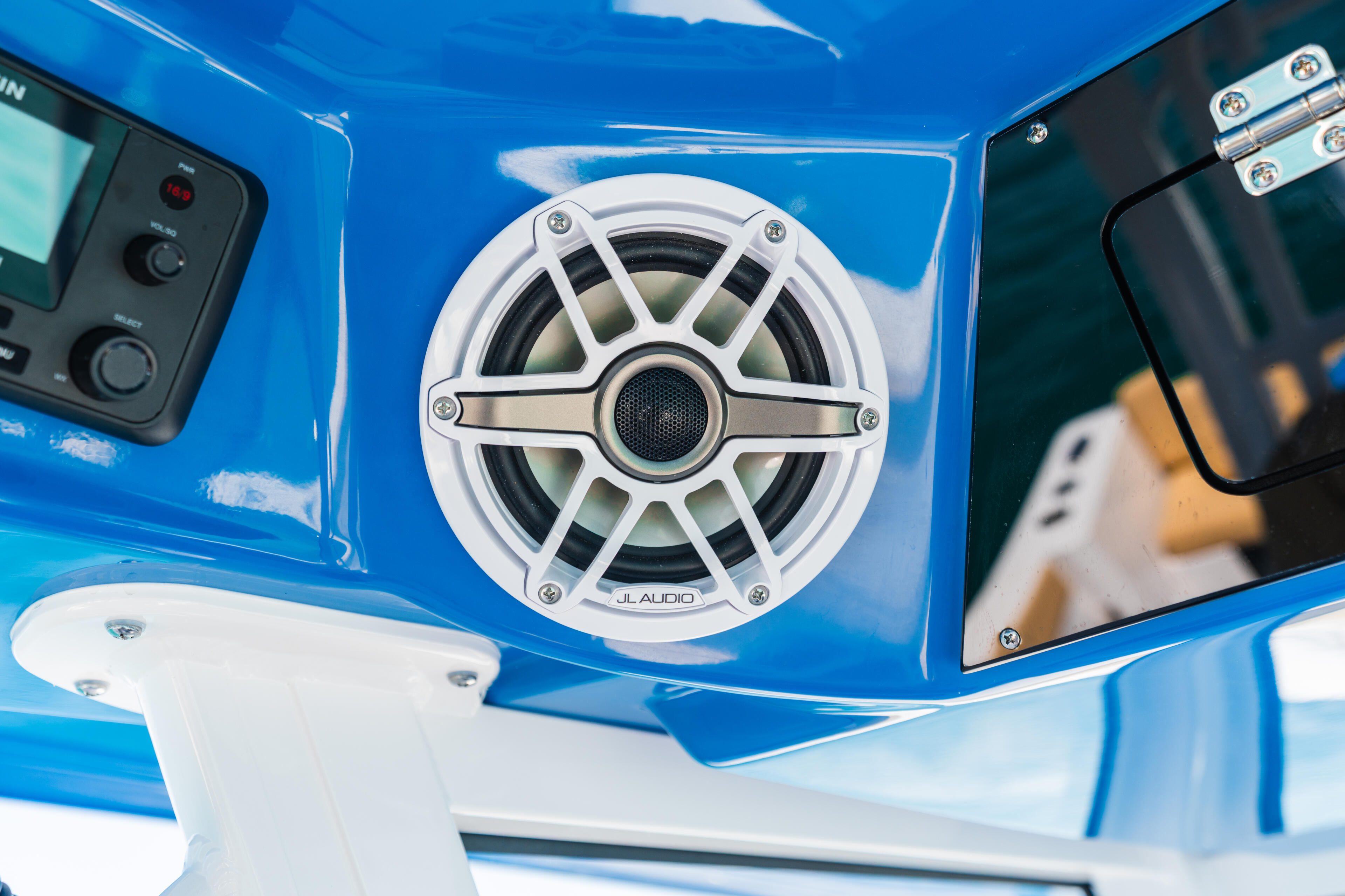 White JL Audio speaker mounted on bright blue hardtop with helm controls and gauge visible