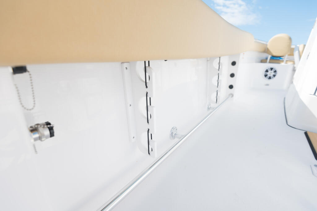 Open gunwale rod racks with white storage compartments and tan canvas shade above deck