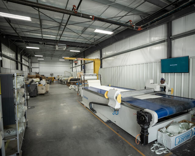Industrial manufacturing facility with CNC cutting equipment and storage materials for boat production