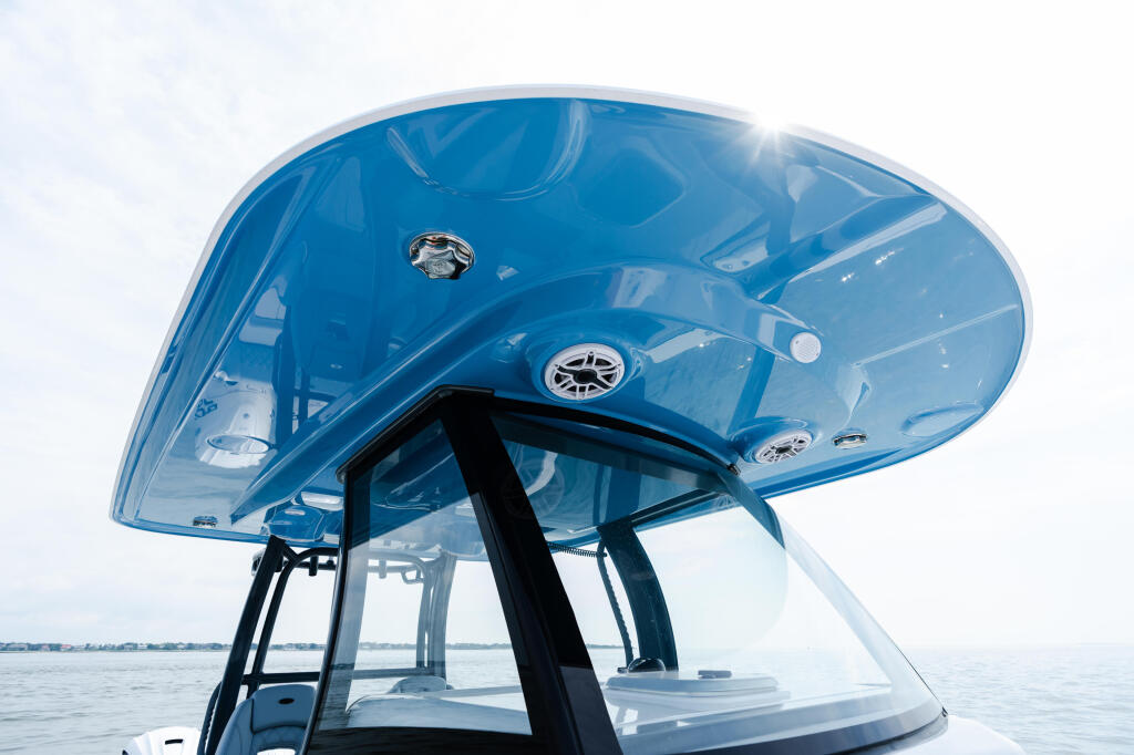 Blue hard-top canopy with ventilation louvers mounted on white boat with calm water and shoreline in background