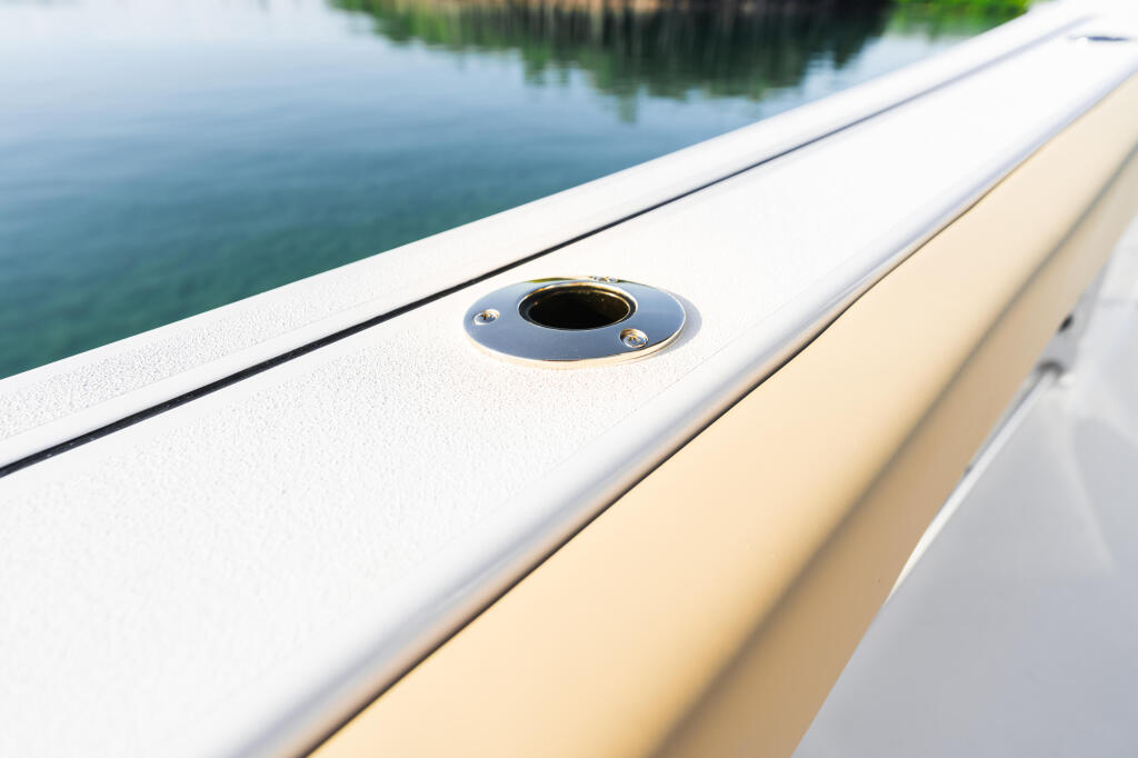 Close-up of boat gunwale with flush-mounted fitting and calm water beyond