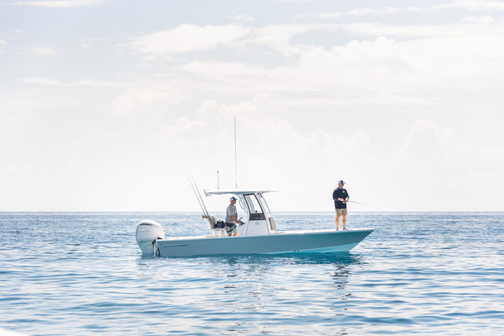 Two anglers on a turquoise center console boat in offshore waters with fishing rods rigged