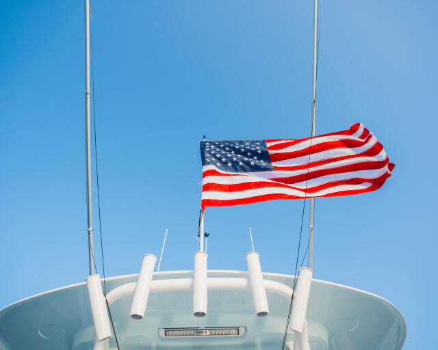 American flag flying from the helm tower of a sportfishing boat against clear blue sky