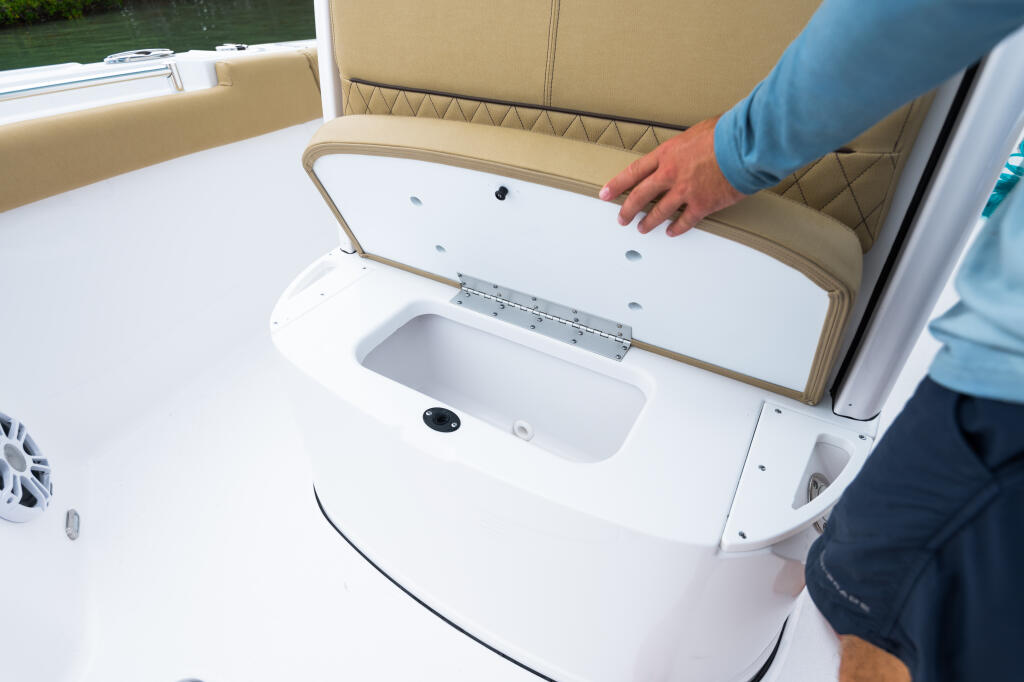Person opening a built-in cooler with tan cushioned seating in the console area