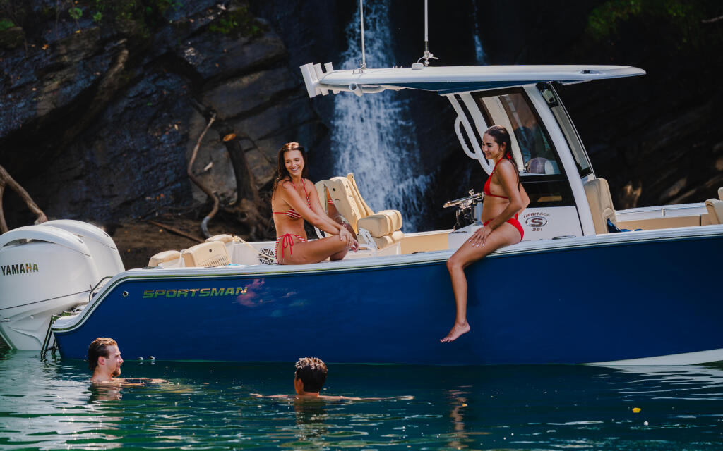 Couples enjoying swimming and relaxation at a scenic waterfall cove from a blue and white Sportsman boat