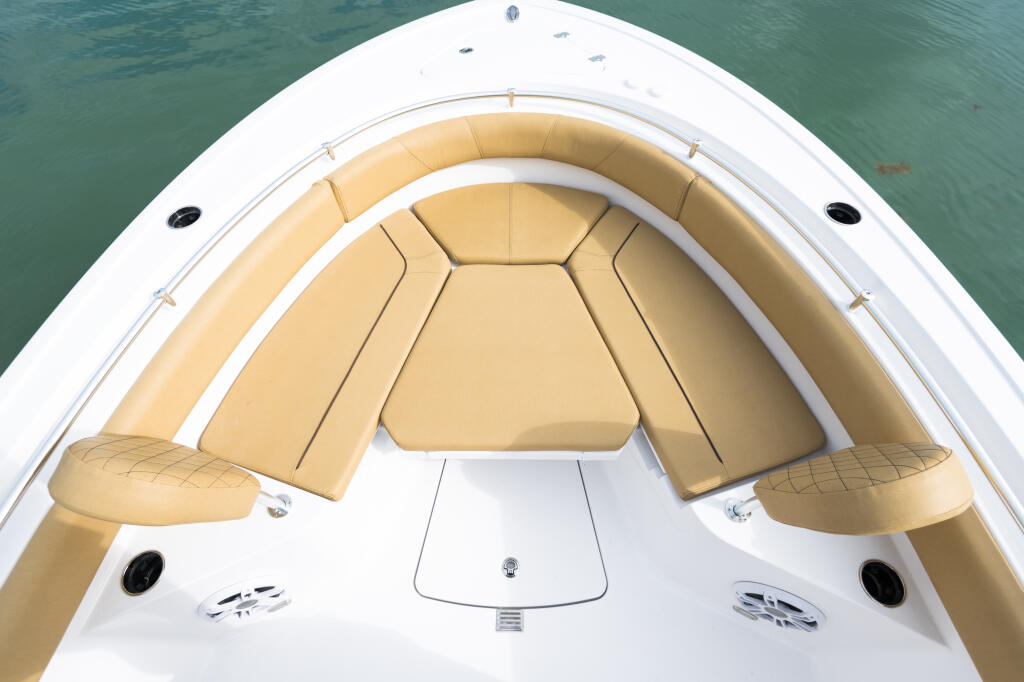 Bow seating area with tan cushions and white gelcoat, viewed from above on turquoise water