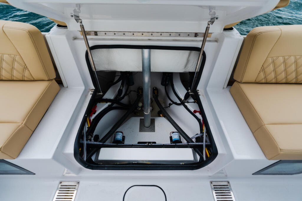 Open engine compartment showing dual fuel tanks, batteries, and wiring on a center console boat