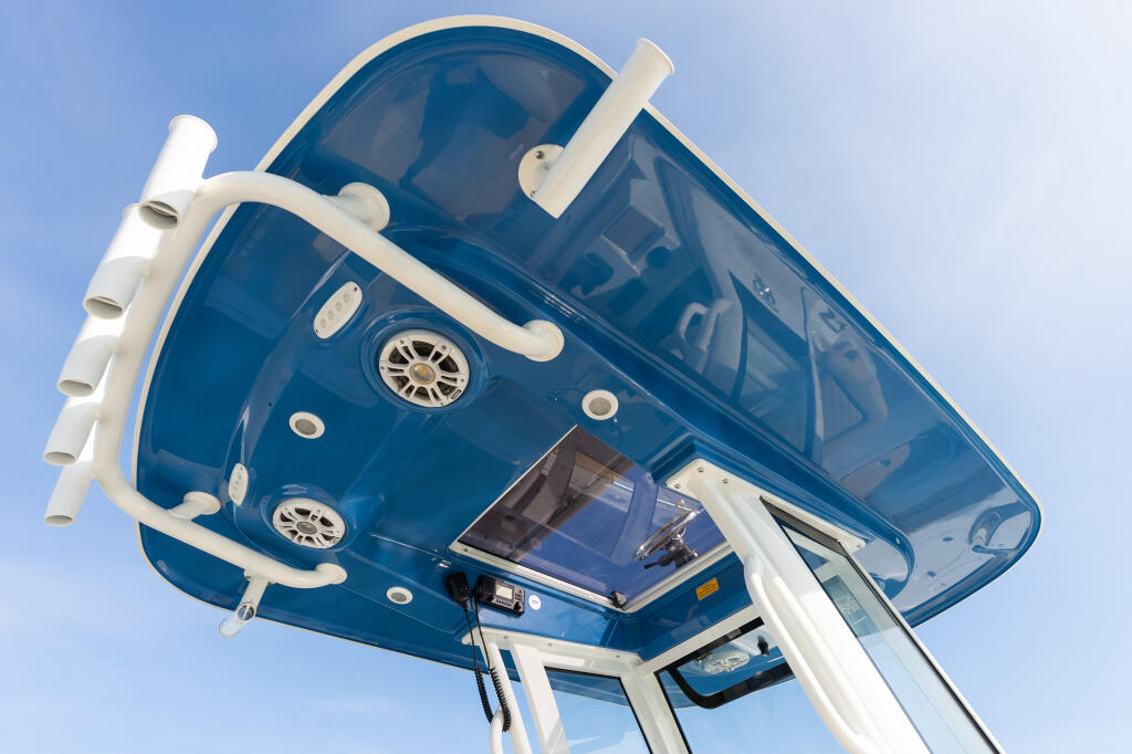 Overhead view of a blue and white center console boat with hard-top, windshield, and railings against clear sky