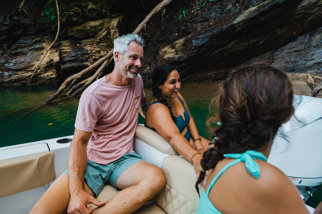 Family and friends enjoying a boat day on a clear lake surrounded by rocky cliffs