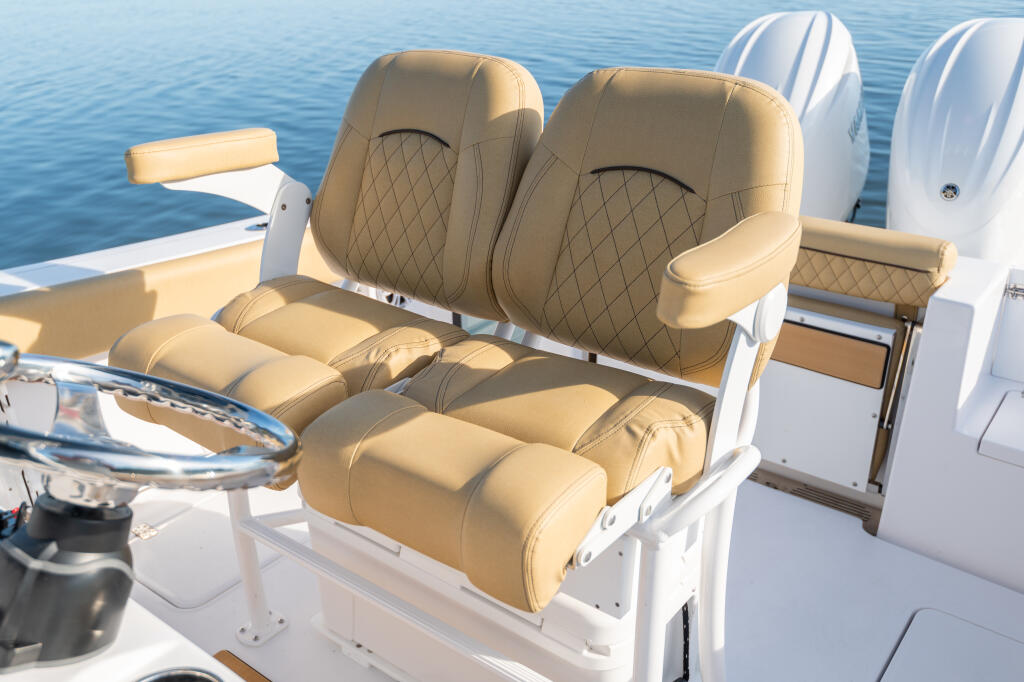 Tan quilted leather captain's chairs with armrests on white center console boat deck overlooking calm blue water