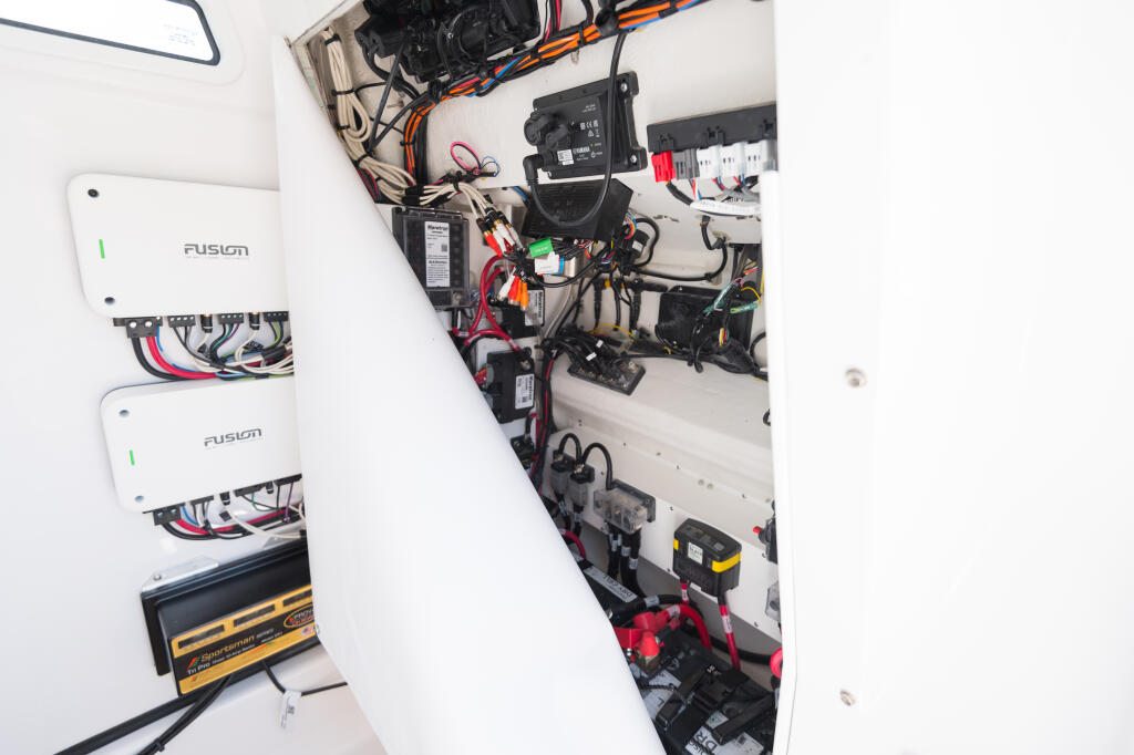 Boat engine compartment with Fusion audio systems, wiring, battery, and electrical components installed on white bulkhead
