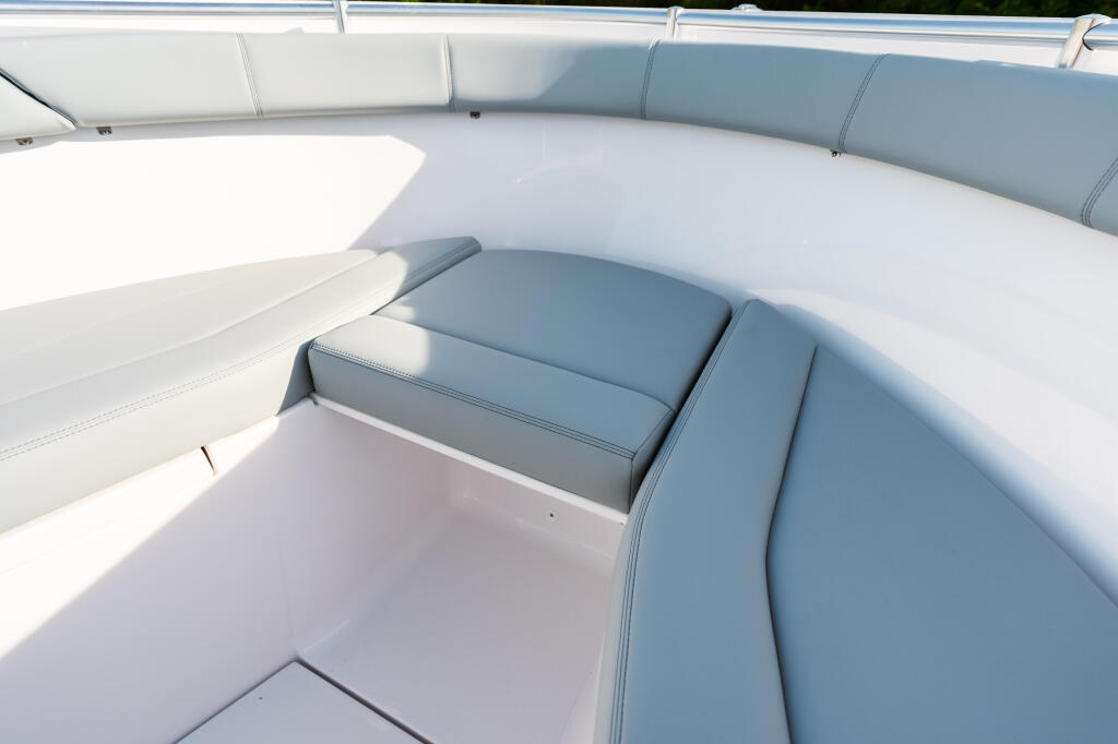 Curved gray and white upholstered seating with storage compartment in boat cockpit