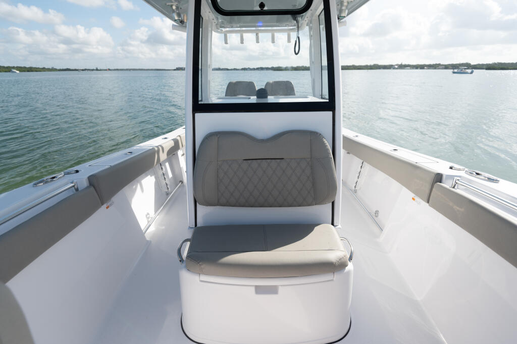 Center console boat interior with gray quilted seating, open deck, and calm water view through the windshield
