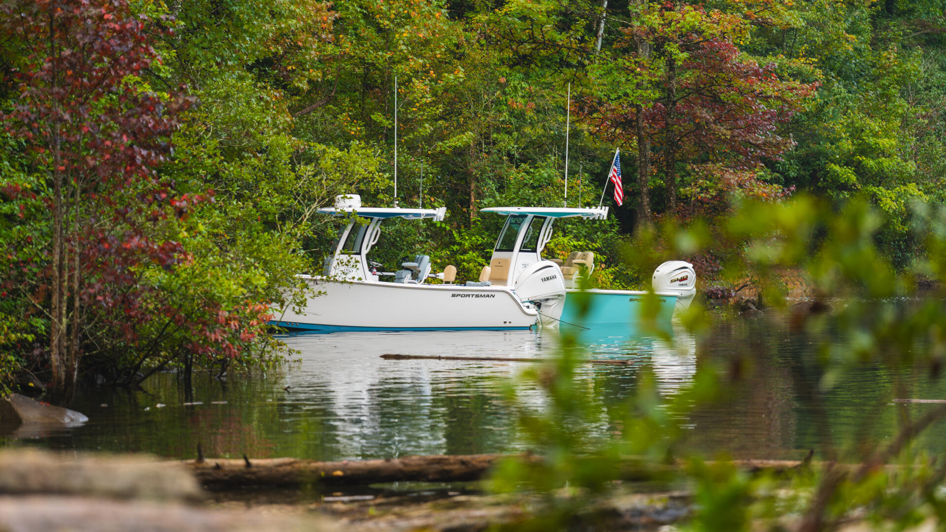 Sportsman boat anchored in calm waters surrounded by autumn foliage and dense trees