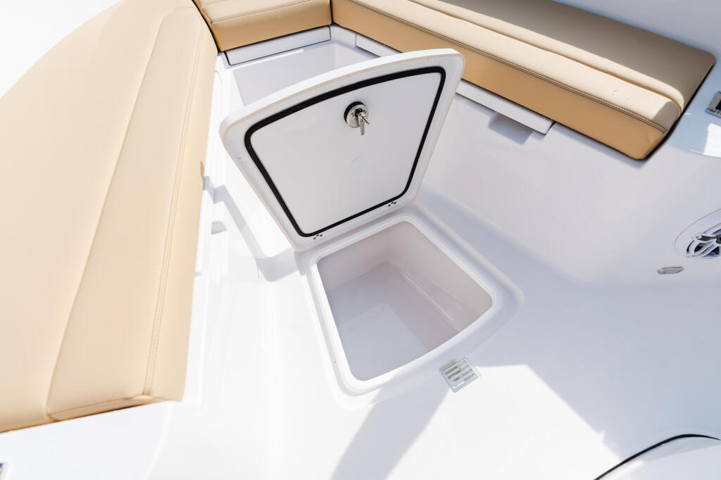 Overhead view of boat storage compartments with cream-colored seating and white deck