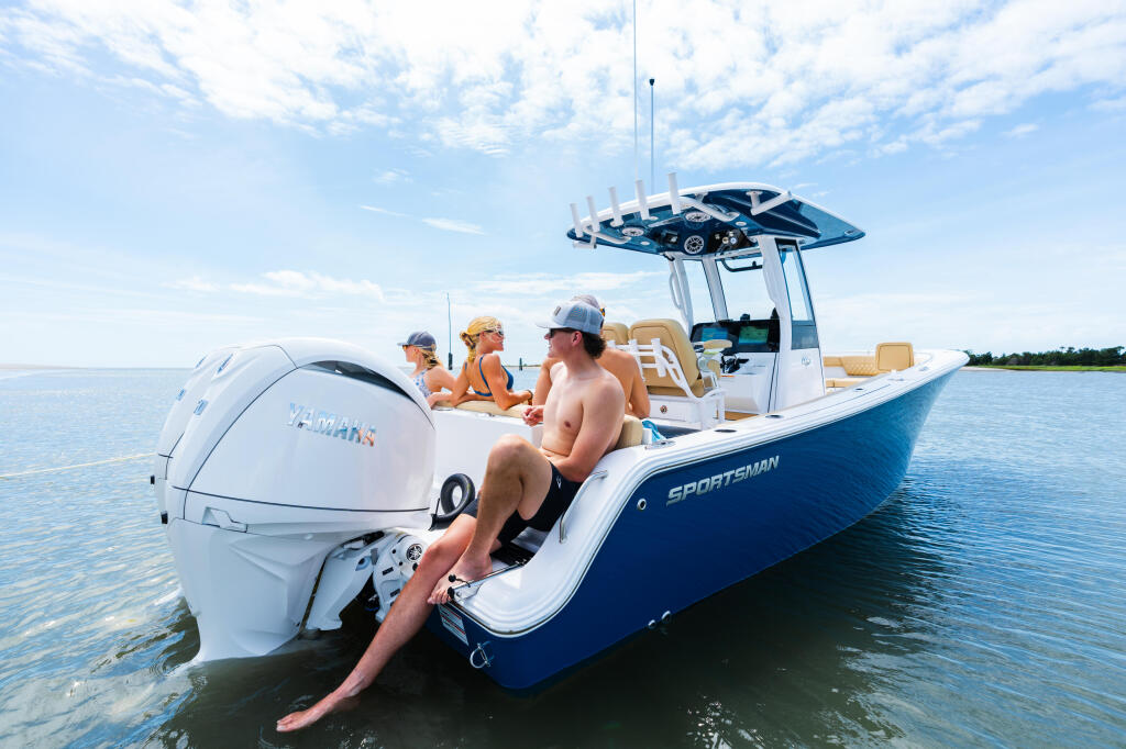 Couple relaxing on a blue and white Sportsman boat in shallow sandbar waters with friends on board