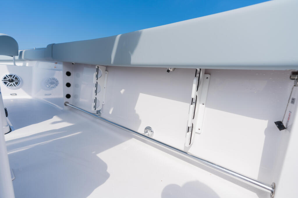 Clean white fiberglass side of center console boat showing rod storage racks and equipment mounts under hardtop