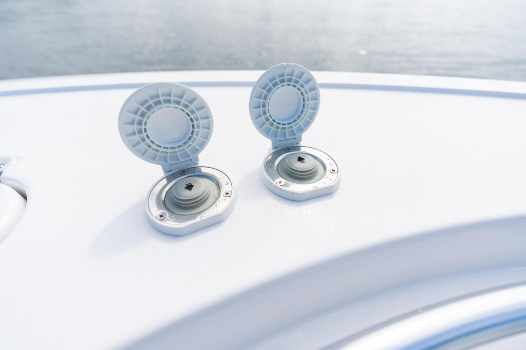 Two white ventilation hatches mounted on the boat's white deck with water visible in background