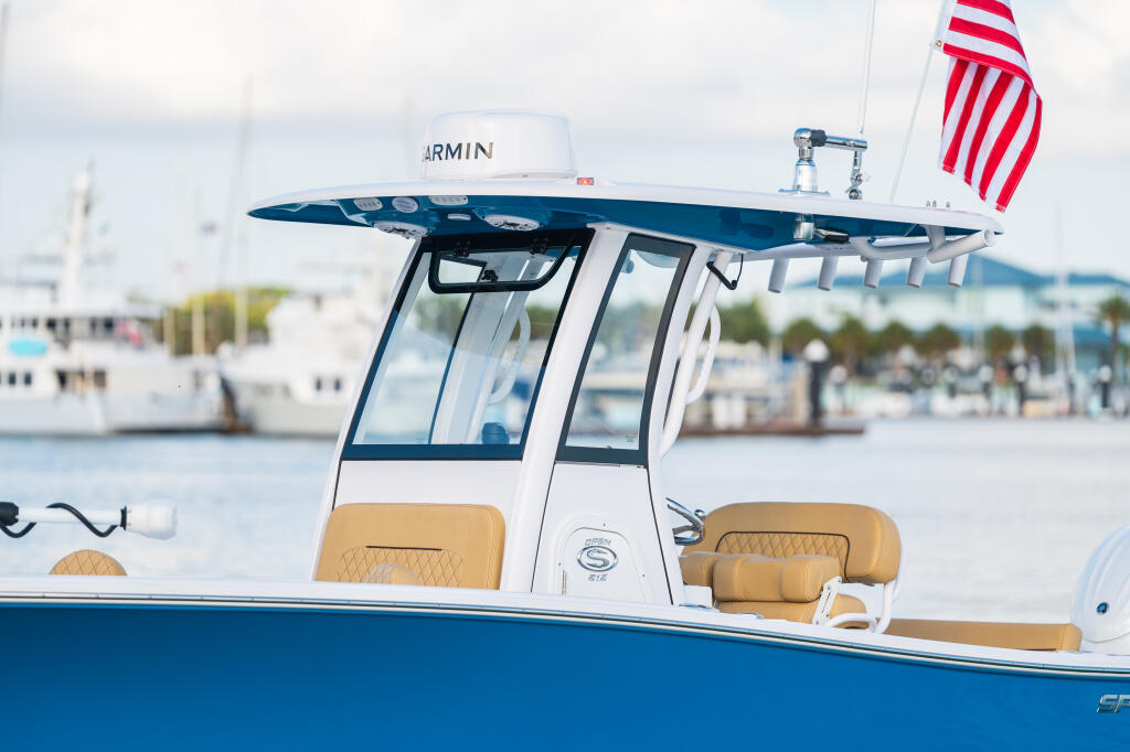 Center console boat with hard-top at a marina, featuring tan seating and Garmin electronics on the helm