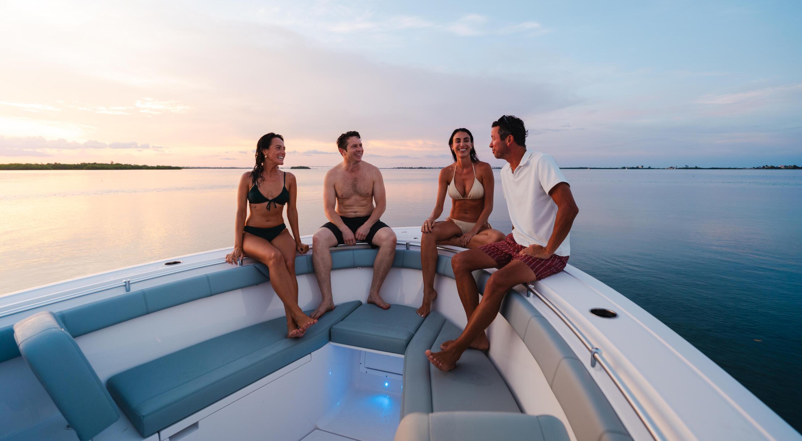 Four friends relaxing on a boat deck at sunset over calm water
