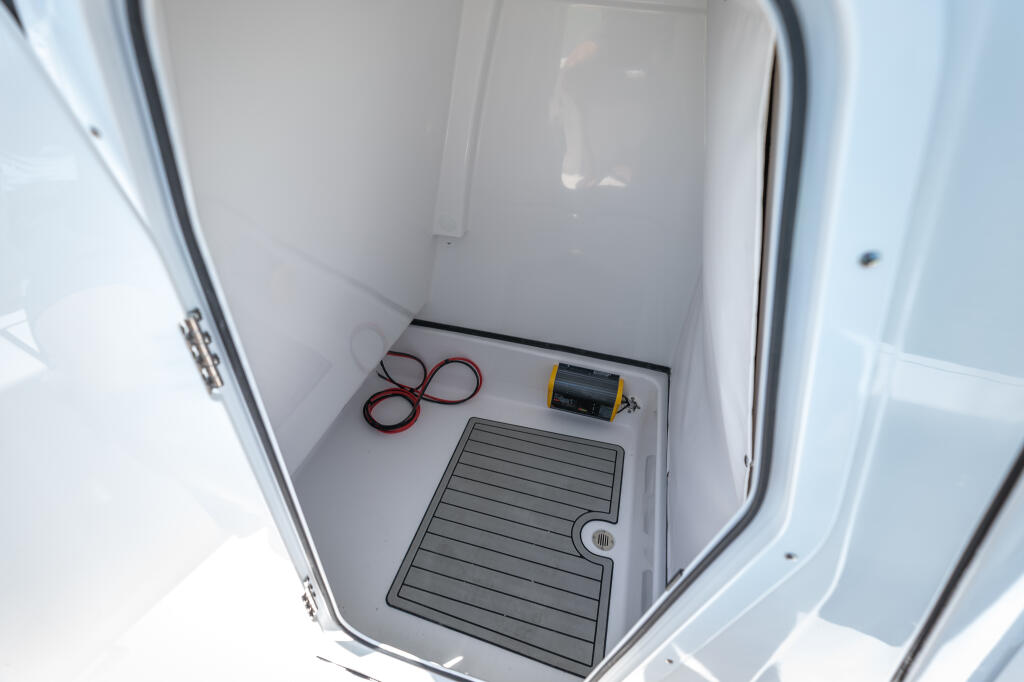 Enclosed head compartment with rubber mat flooring, electrical panel, and coiled red cables