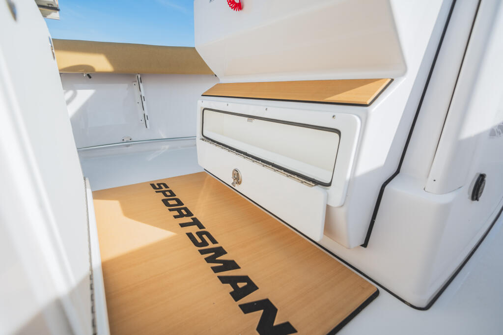 Cabin interior with wood flooring, white cabinetry, overhead storage shelves, and companionway door with portlight window