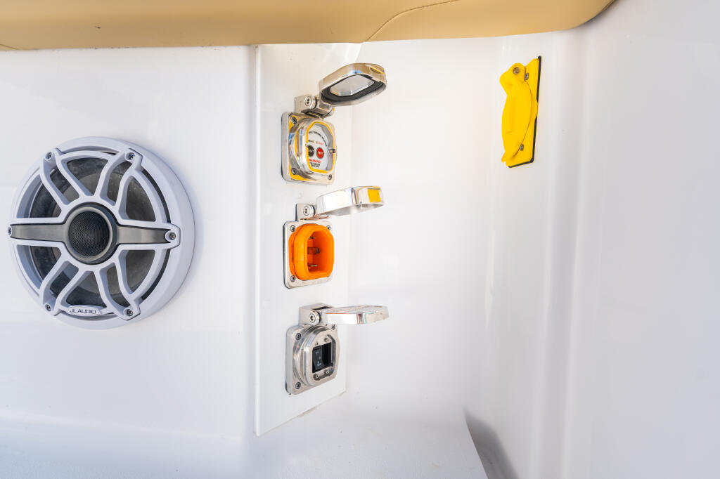 Boat cabin wall showing marine audio speaker, electrical outlets with yellow covers, and stainless steel hardware