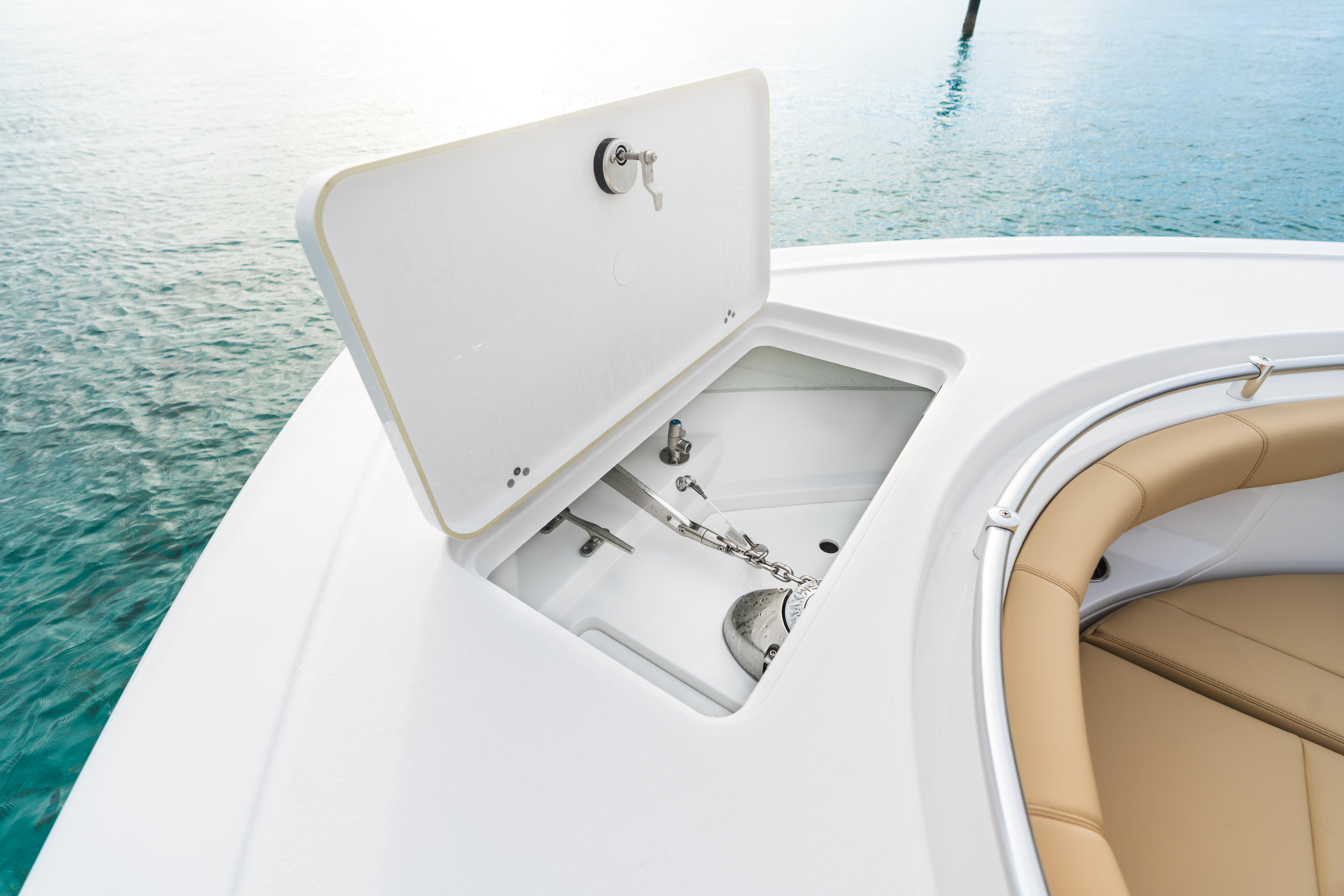 Open storage locker with windlass anchor system and mechanical controls on white boat hull
