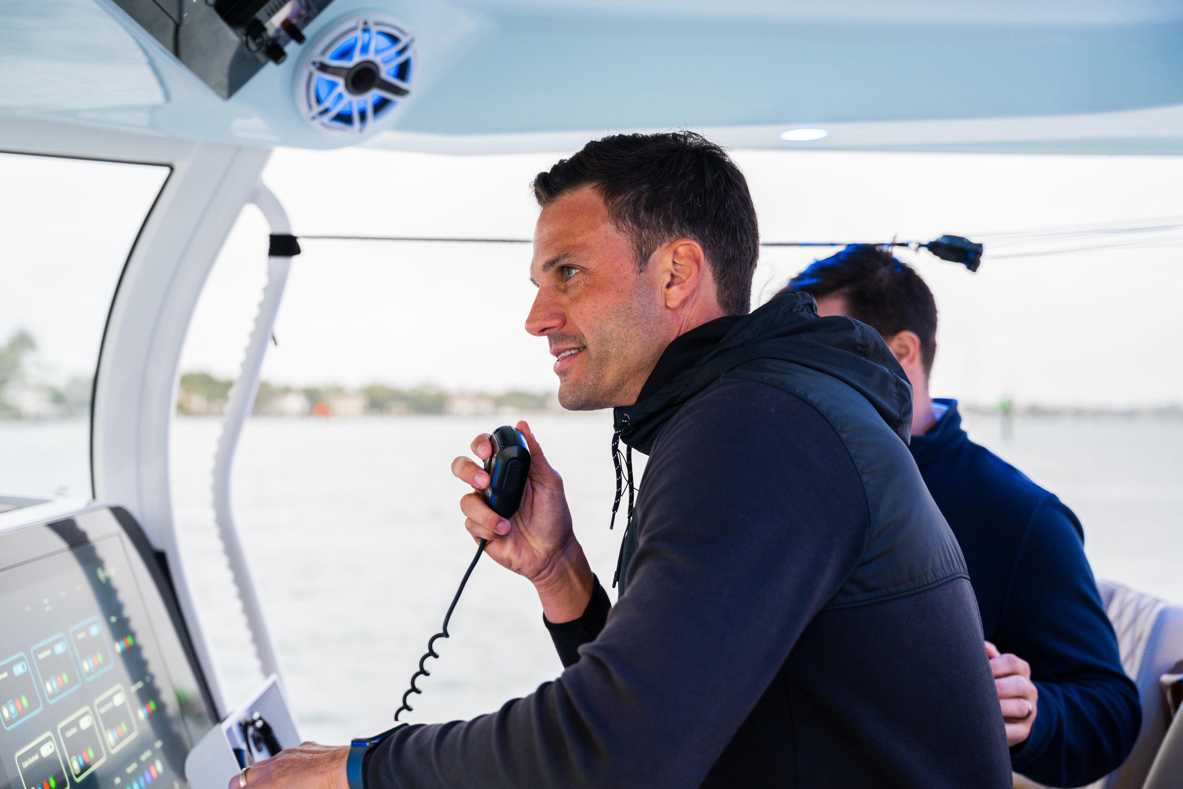 Man at the helm operating boat electronics and communication systems while cruising on open water