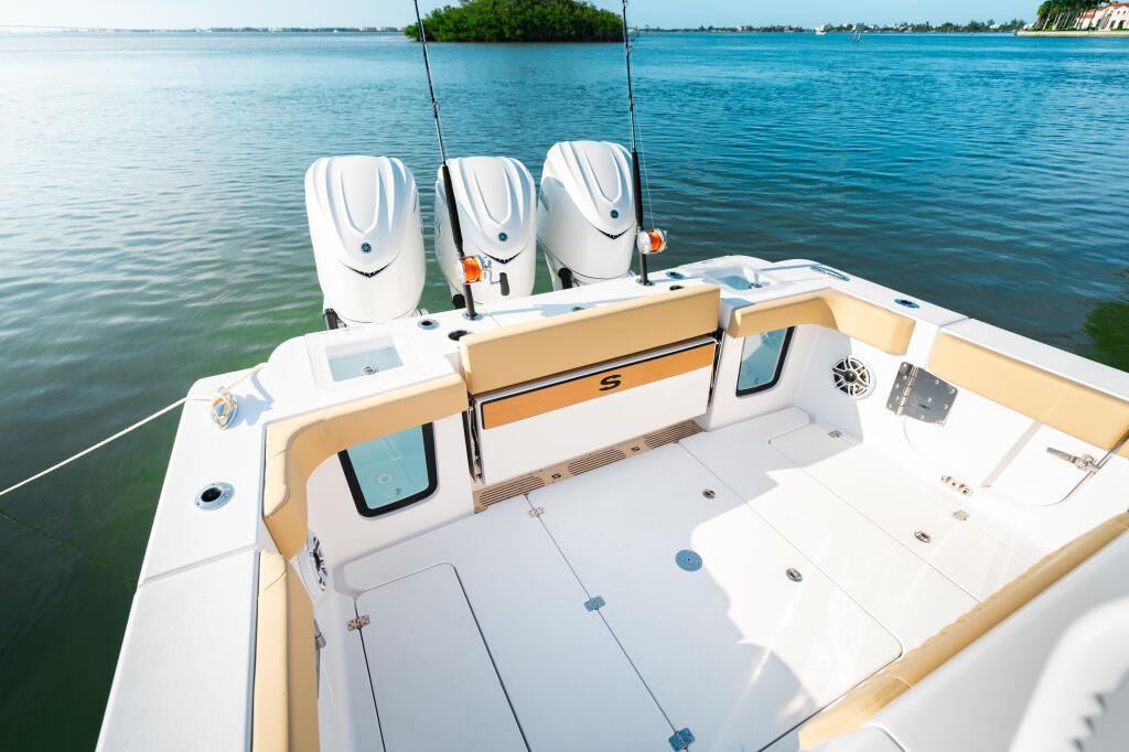 Triple outboard engines and spacious open cockpit with tan accents on center console fishing boat