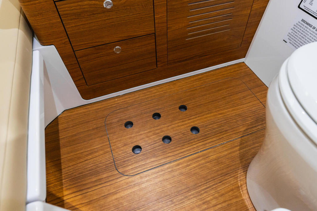 Wooden cabin floor with ventilation holes and toilet visible in compact boat interior