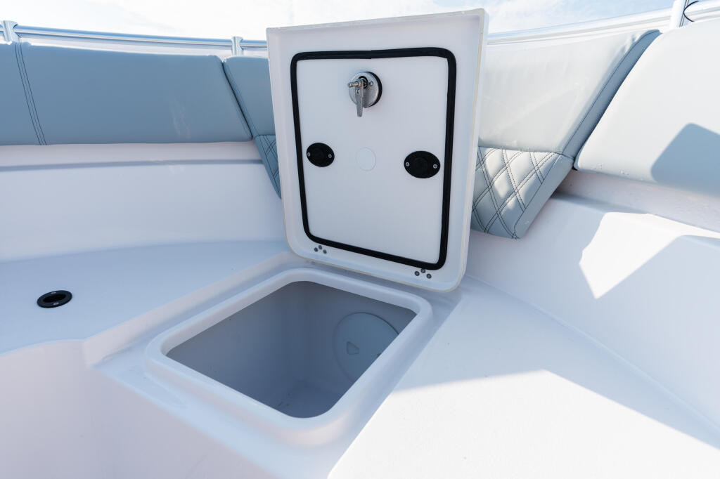 Open cabin door and storage compartment on boat deck with blue cushioned seating visible