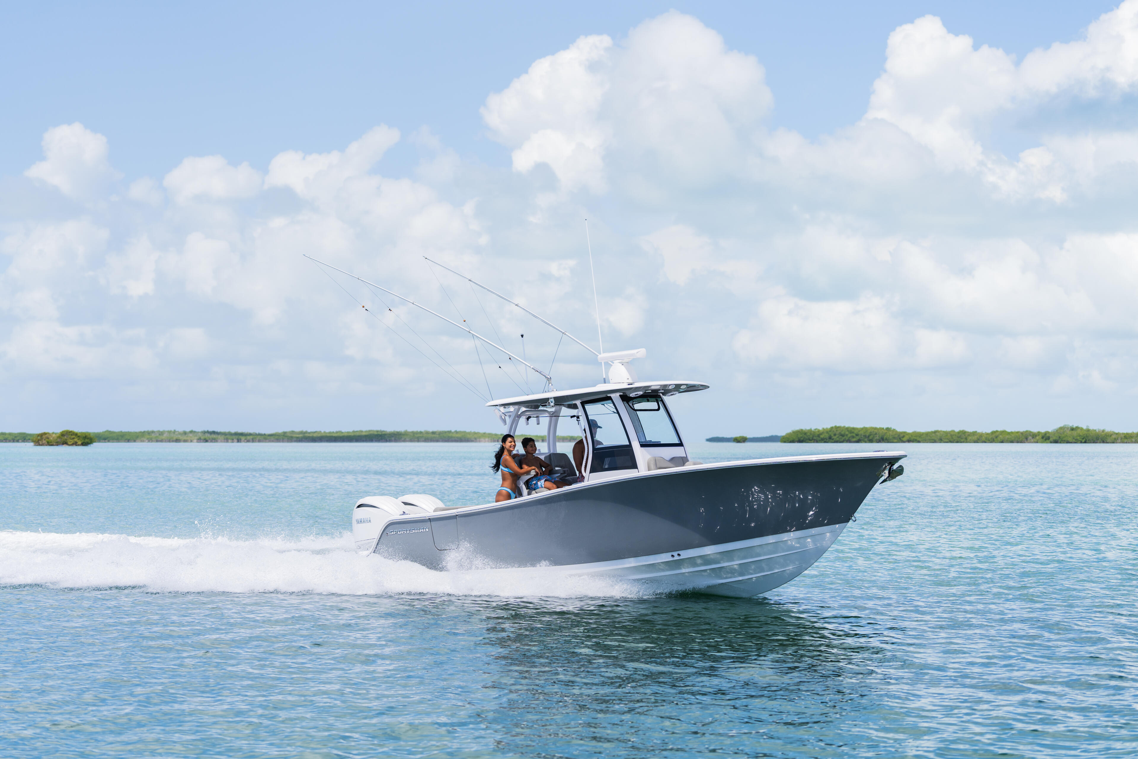Family enjoying a day on a center console fishing boat running through shallow turquoise waters near mangroves