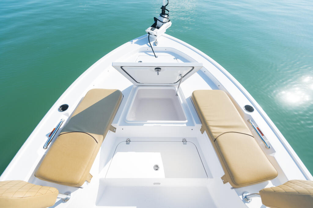 Aerial view down the center of a white boat's bow with tan seating and an open fish box