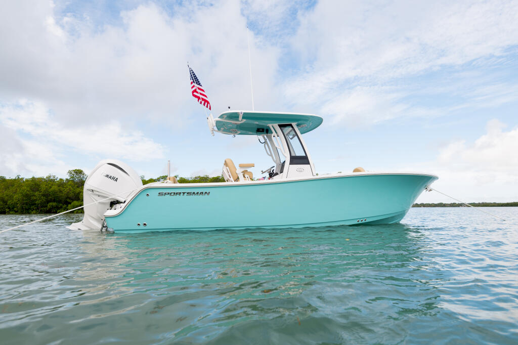 Turquoise Sportsman center console boat anchored in shallow tropical water with hard-top canopy and American flag