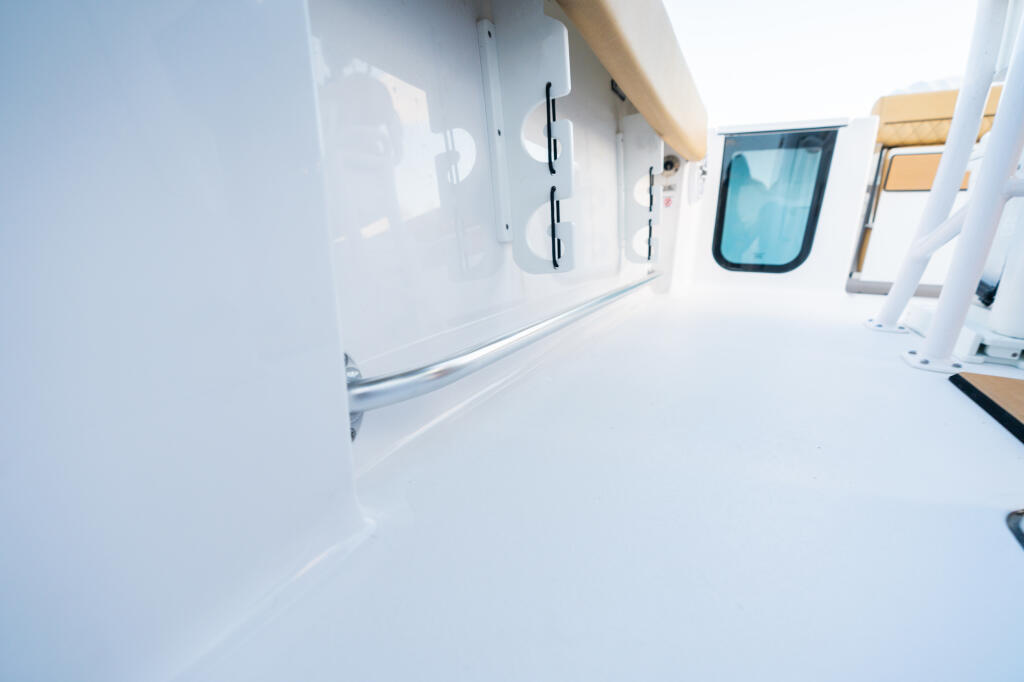 Boat cabin interior with white walls, windows, and teak accents along the starboard side