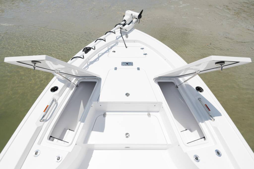 Overhead view of a white center console boat with twin engines and open bow seating in shallow water