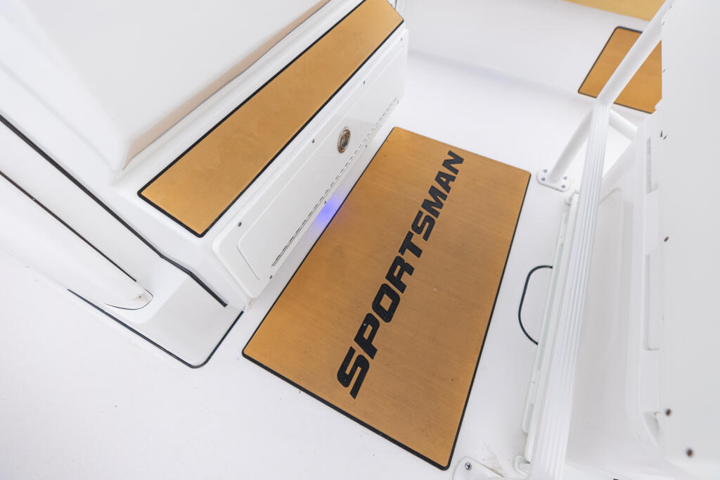 Sportsman branded tan anti-fatigue mat installed at boat helm with white fiberglass deck and electronics visible
